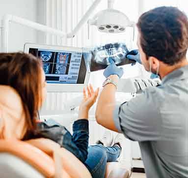 Dentist going over x-ray results with a woman wearing jeans